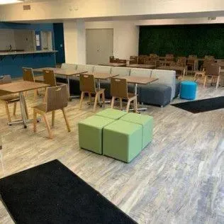 A large room with tables , chairs , ottomans and a couch.