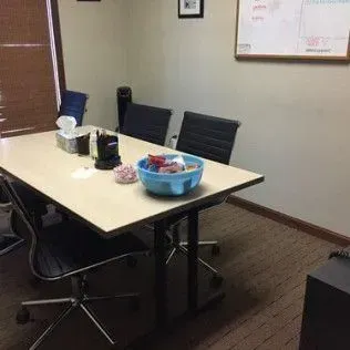 A conference room with a table and chairs and a whiteboard.