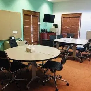 A conference room with tables and chairs and a television on the wall.