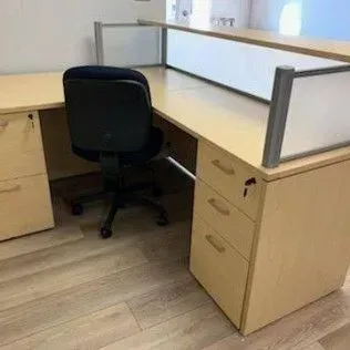 A cubicle with a desk and a chair in an office.