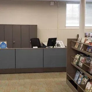 A library with a desk and shelves filled with books.