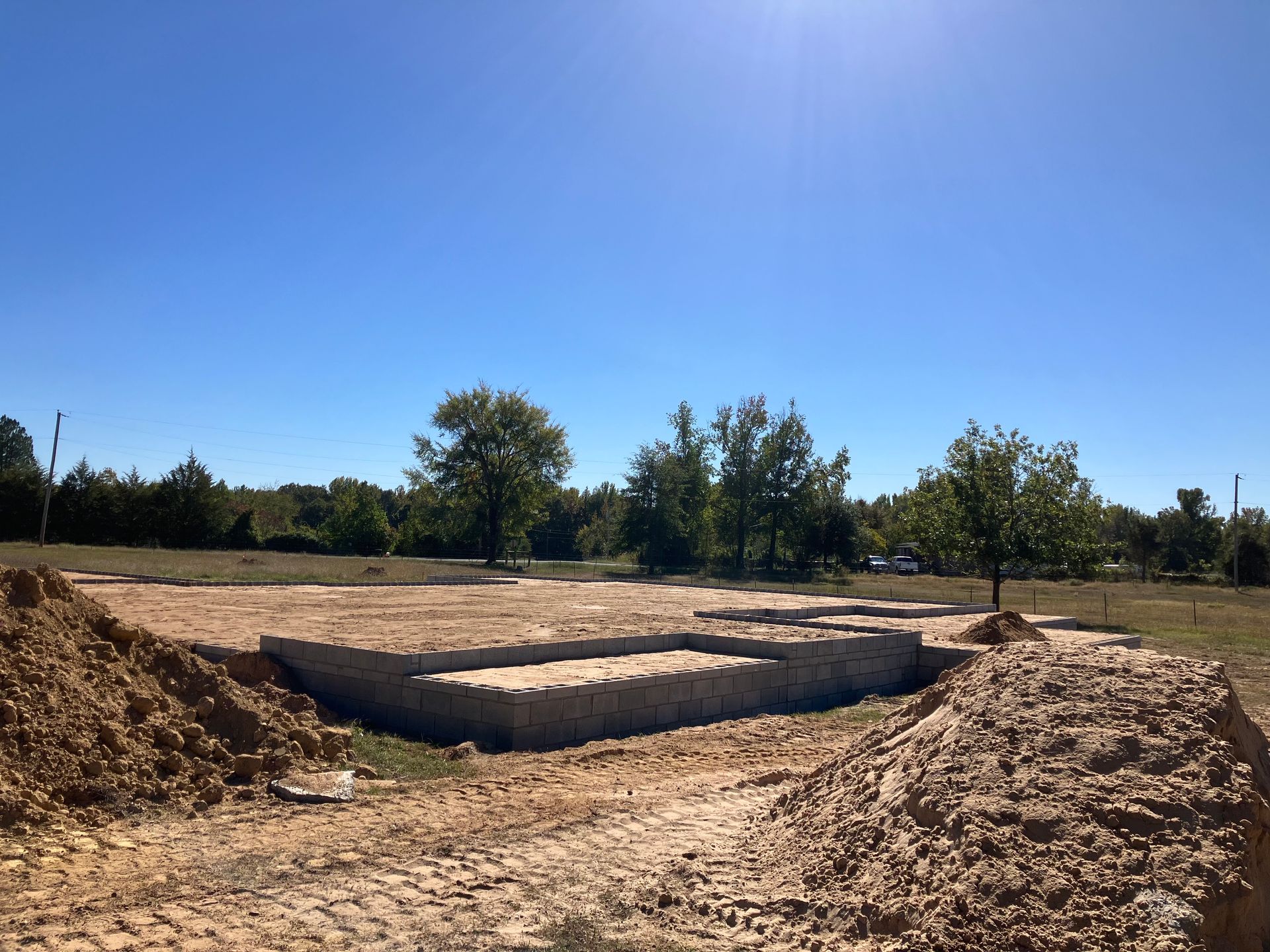 A dirt field with trees in the background and a blue sky