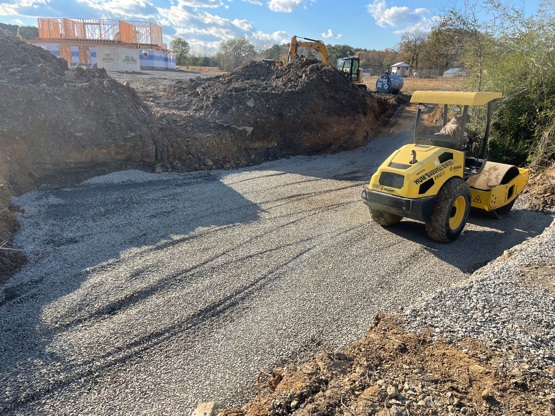 A yellow and black machine is driving down a gravel road.
