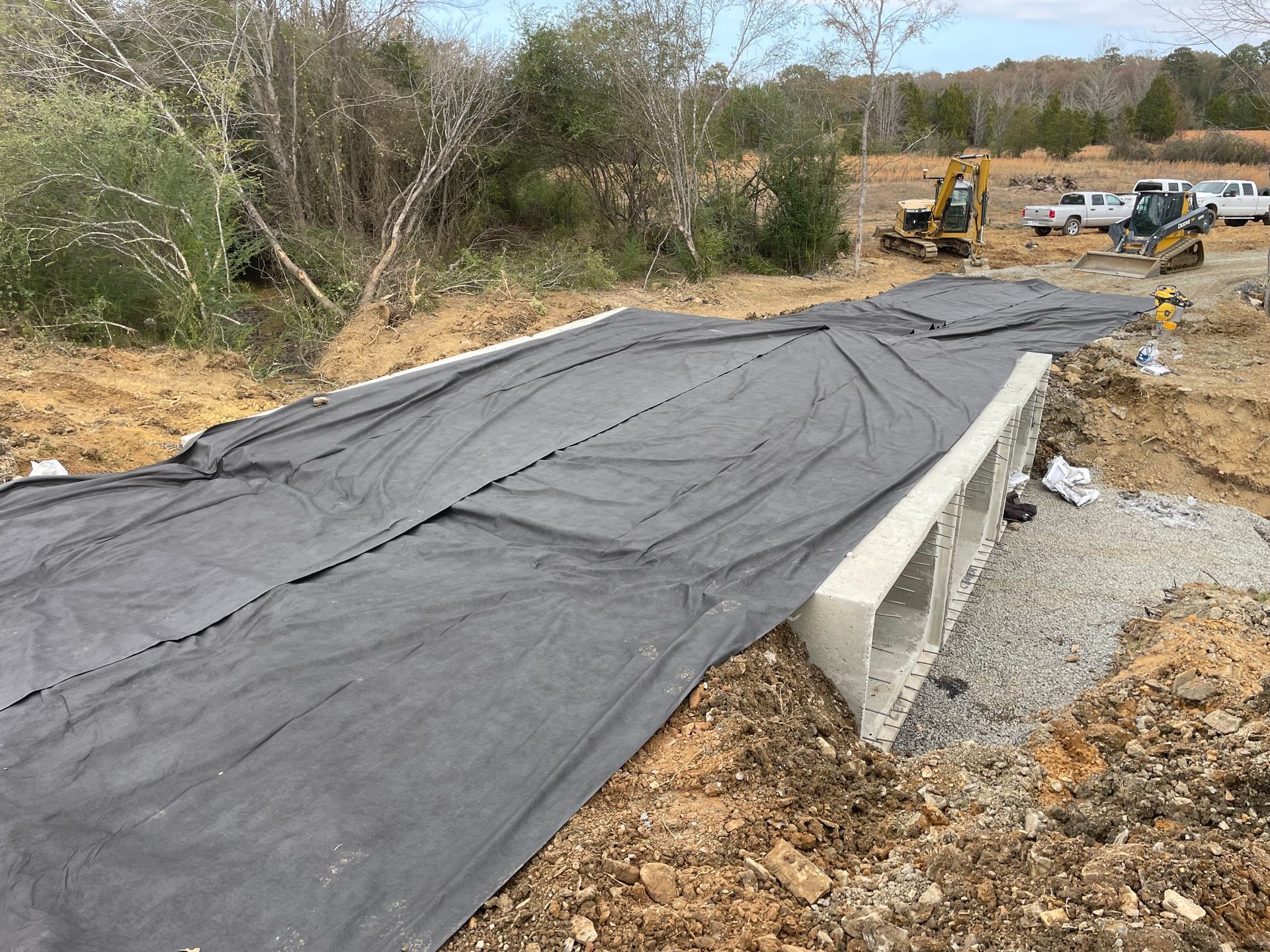 A tarp is covering a concrete structure in a field.