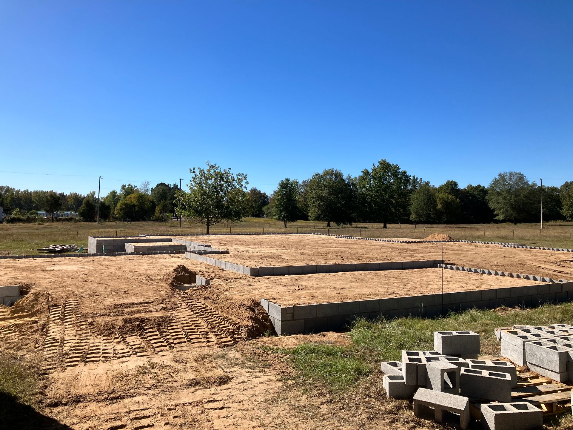 A construction site with a blue sky and trees in the background