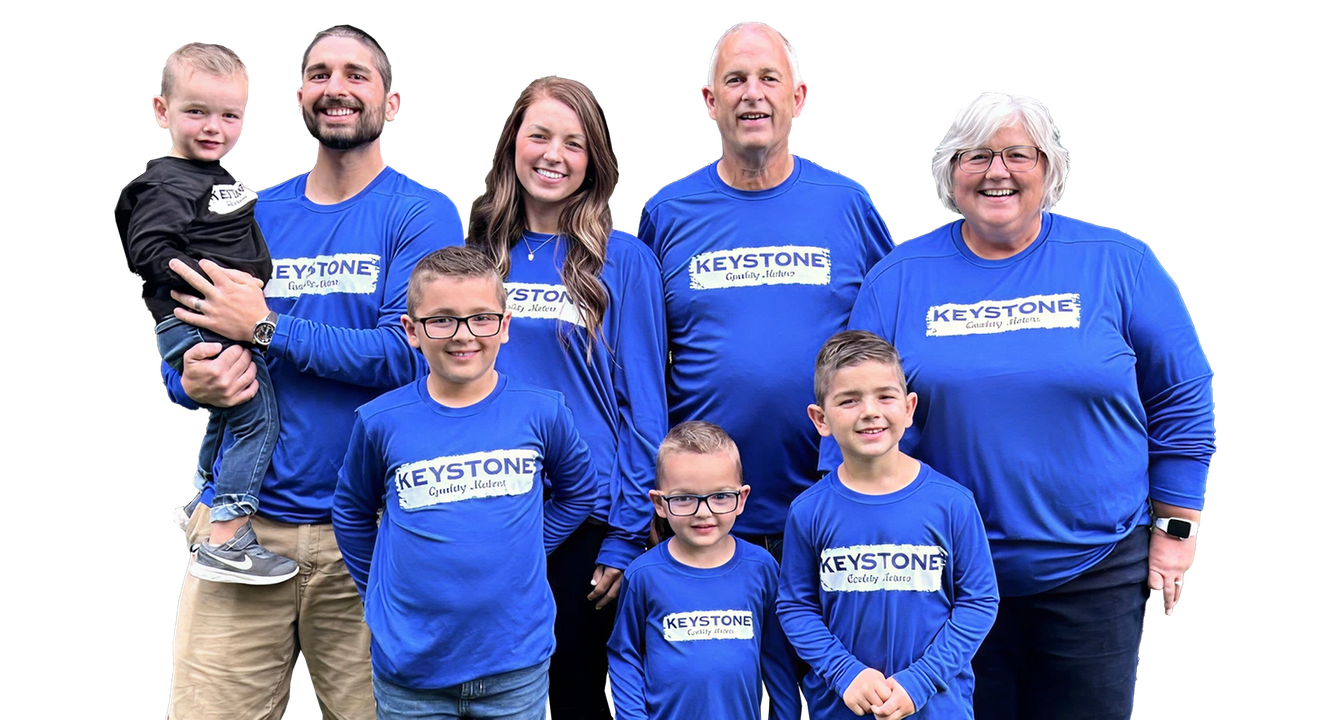 Group of seven people in matching blue shirts posing together against a white background | Keystone Quality Motors