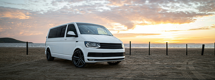 White van parked on a beach at sunset with the ocean and fence in the background | Keystone Quality Motors