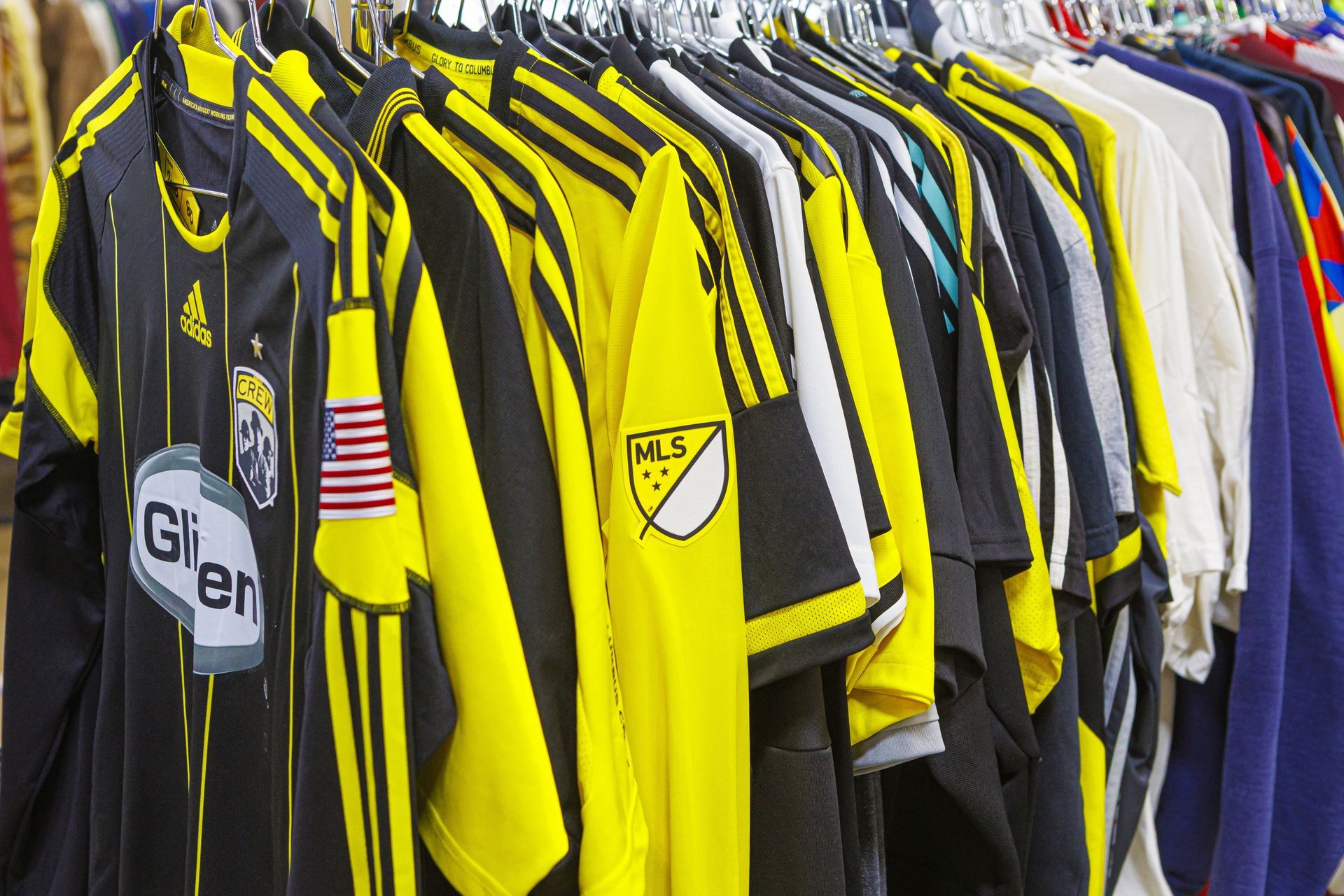 Soccer jerseys on clothing rack; various colors including black, yellow, and blue.