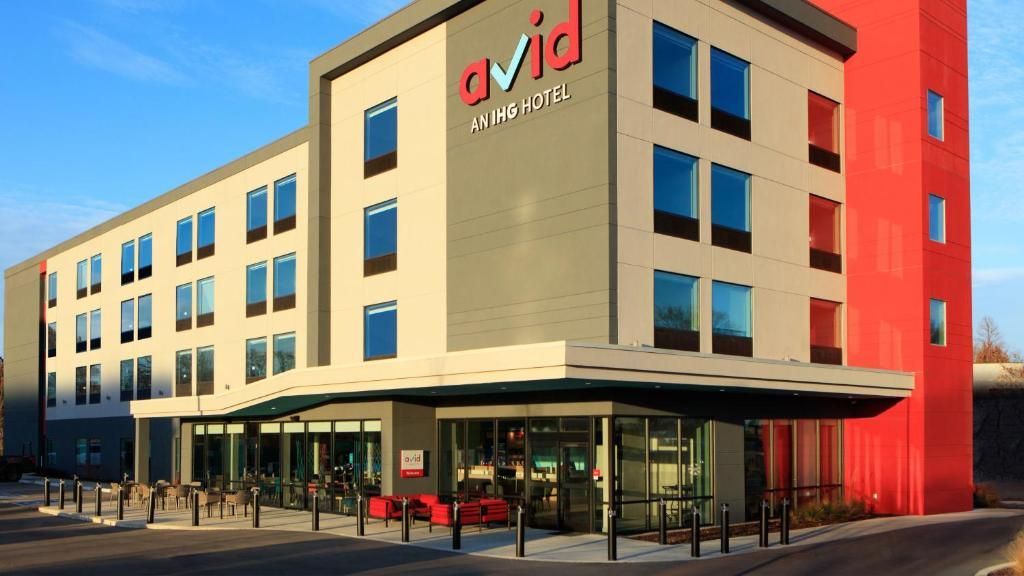 Exterior of Avid Hotel building with a gray and red facade.