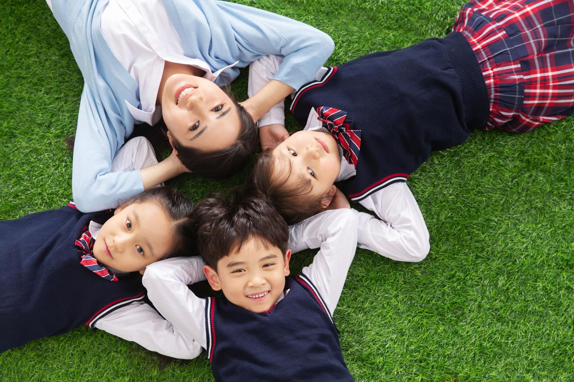 A group of children are laying in a circle on the grass.