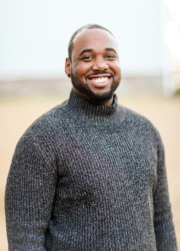 A man in a suit and plaid shirt is smiling for the camera.