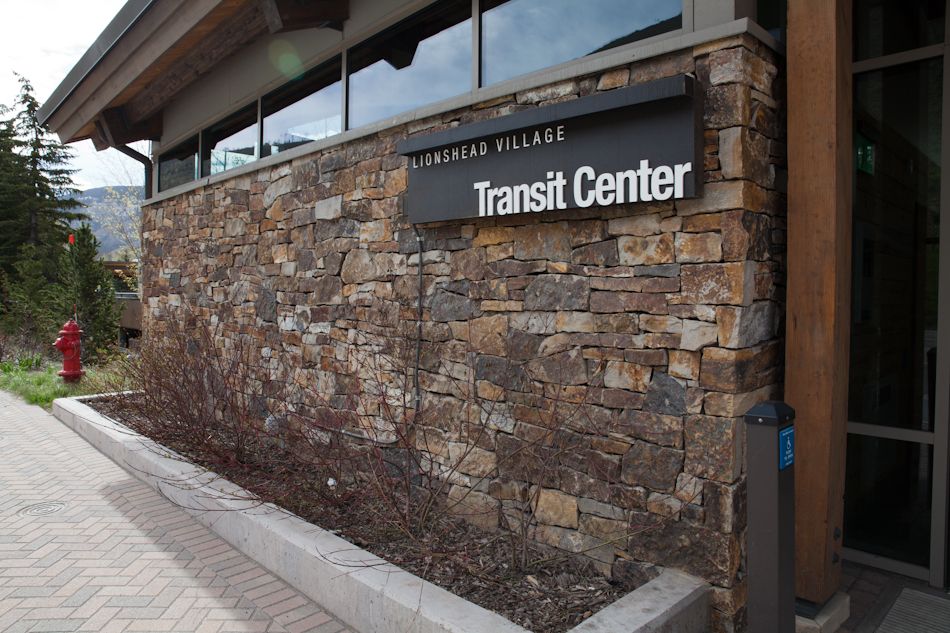 Stone wall exterior of the Mountain Village Transit Center with a sign, a sidewalk, and a fire hydrant nearby.