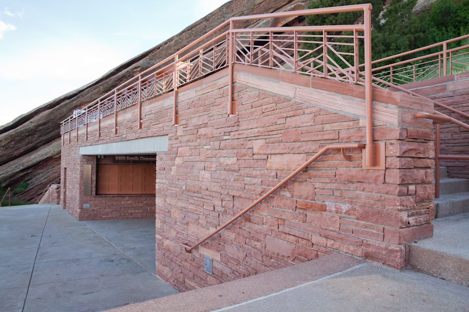 Red sandstone stairs and walkways with metal railings at Red Rocks Amphitheatre under a clear sky.
