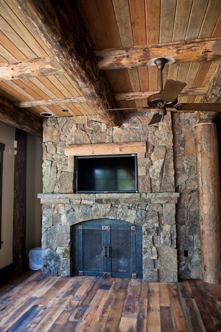 A bright, crackling fire burns inside a large stone fireplace with a stone hearth.