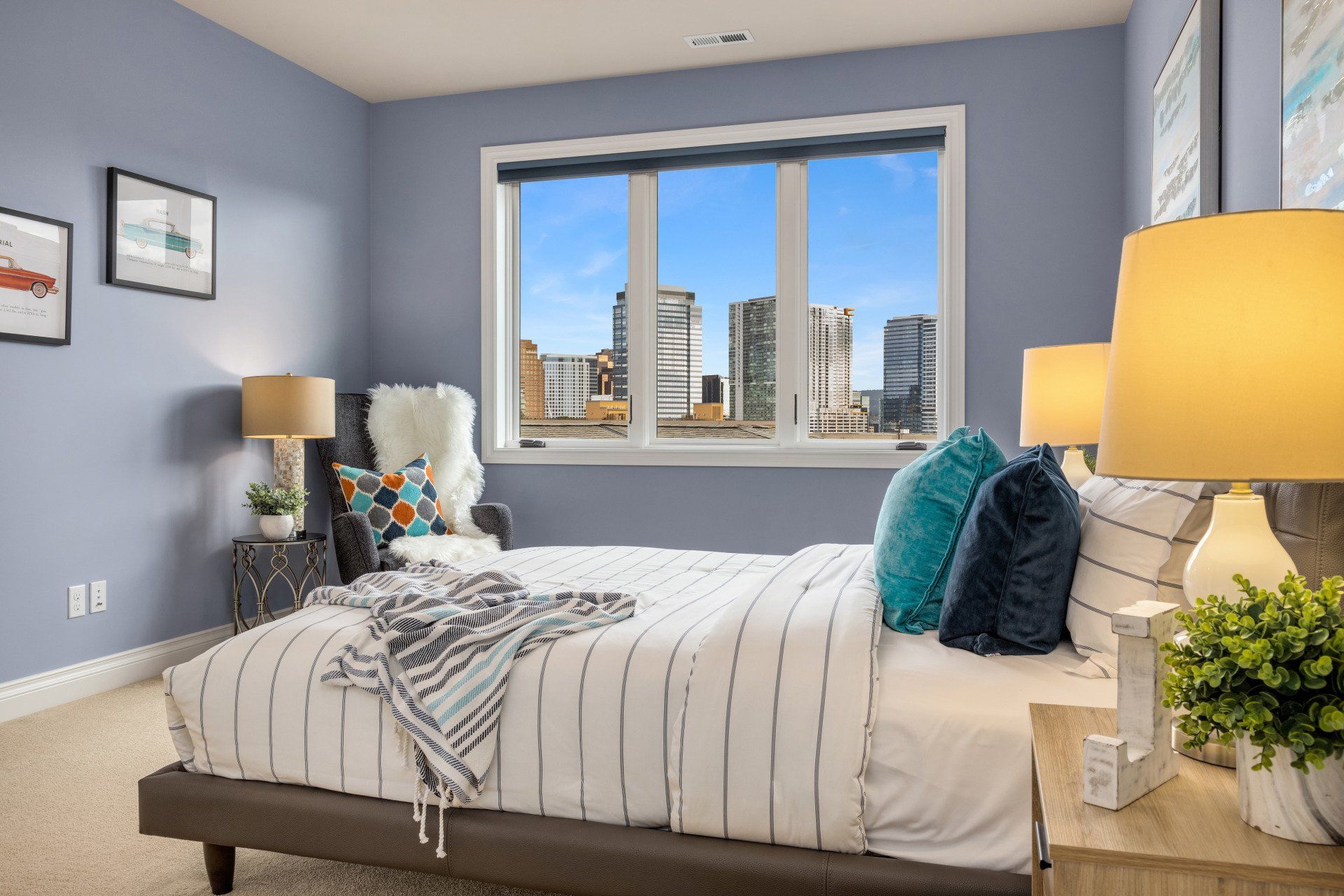 Bedroom with blue walls, a bed, and a cityscape view from the window.