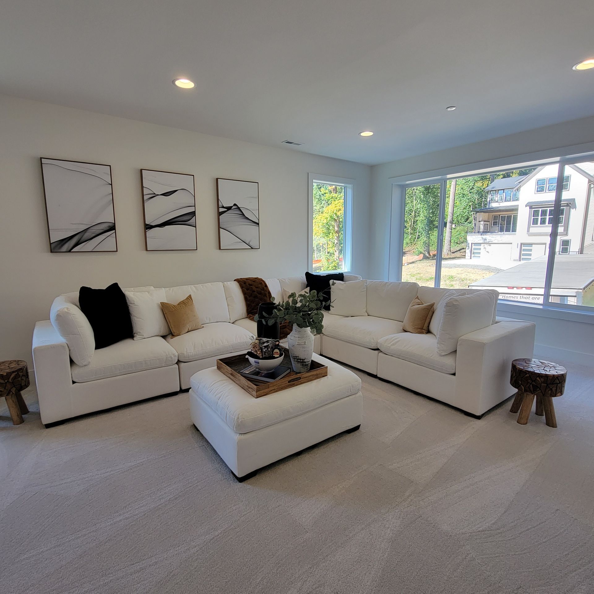 A white living room with white sofas, a white ottoman, and modern art.