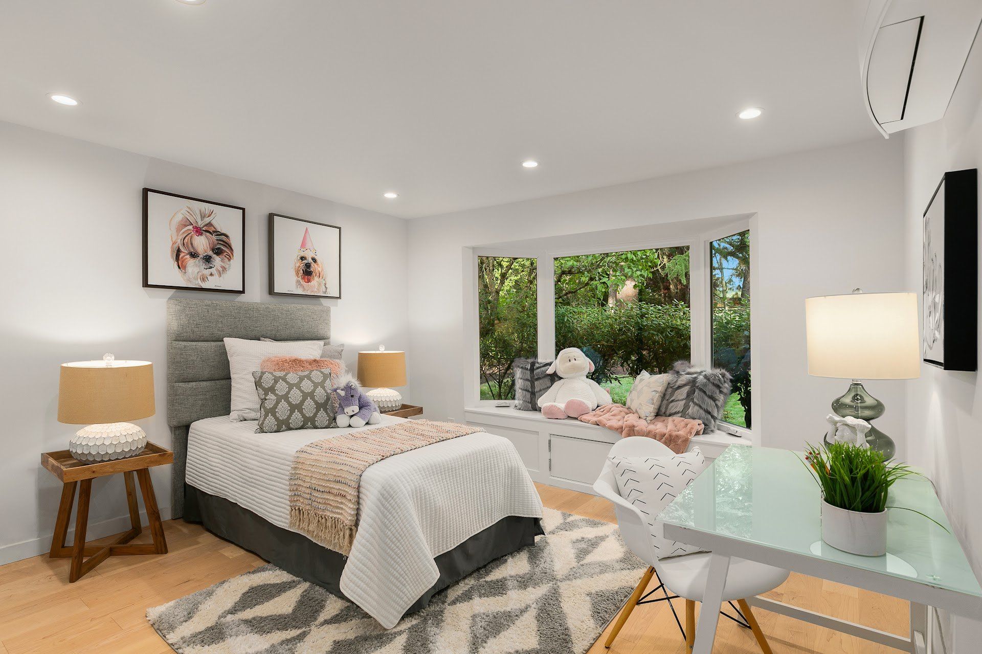 A child's bedroom with a bed, desk, and large window with a plush toy.