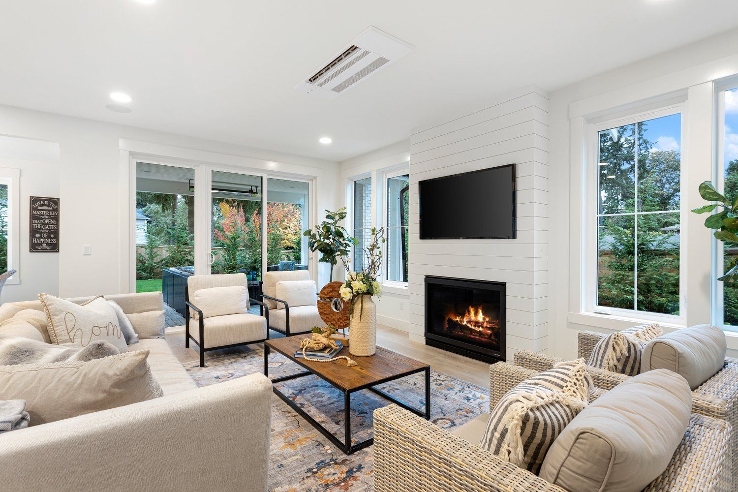 Cozy living room with white walls, fireplace, large windows, and light-colored furniture.
