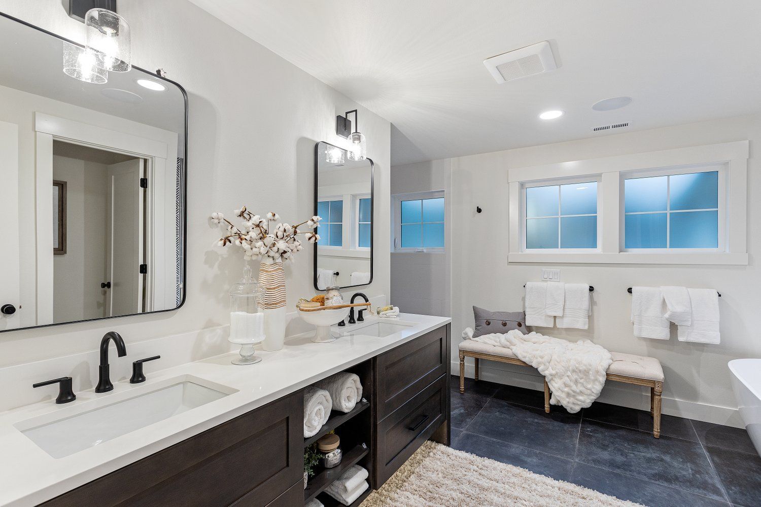 Modern bathroom with white walls, dark vanity, and black fixtures.