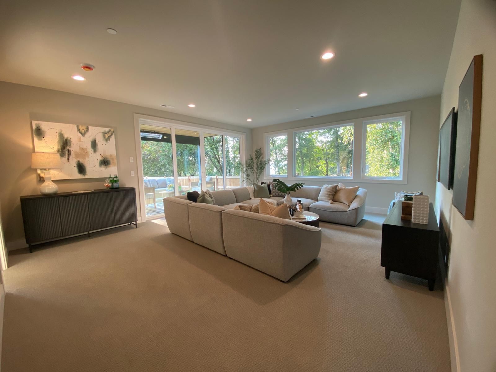 Living room with sectional sofa, large windows, and neutral color scheme.