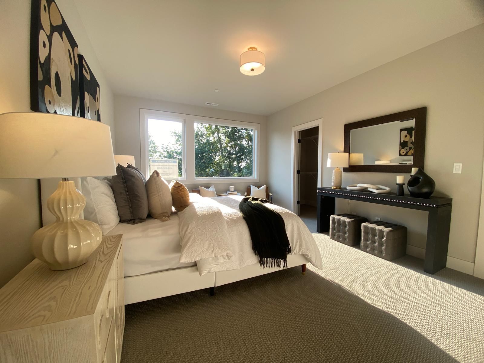 Bedroom with a large bed, windows, and decorative furniture; neutral color palette.