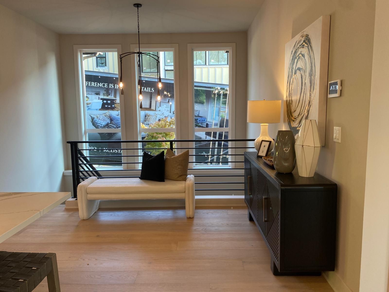 Hallway with bench, windows, black console table with decor, and a hanging light fixture.