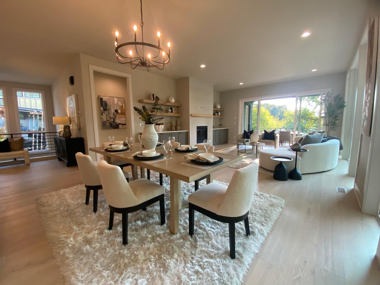 Dining room with table set for six, a chandelier, and a view to a living space and outdoors.