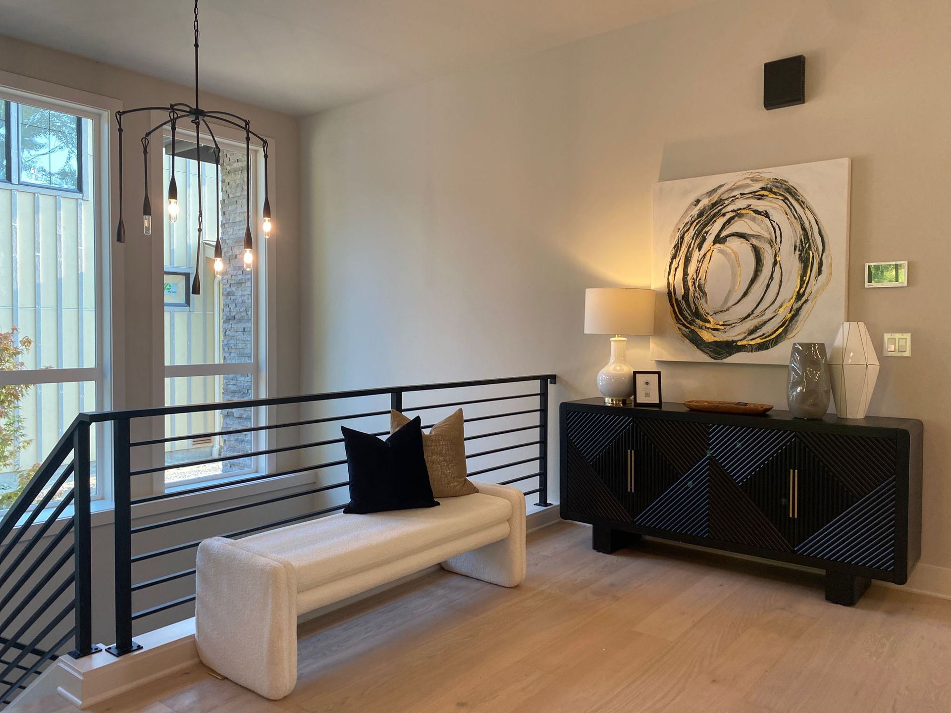 Modern foyer with a white bench, black console, and abstract artwork.