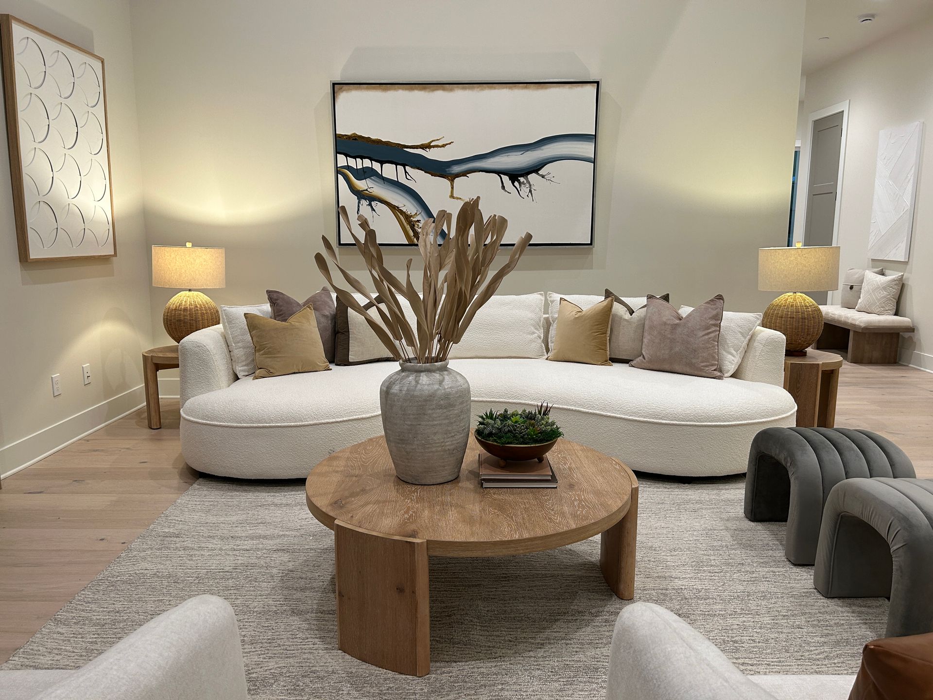Living room with white sofa, coffee table, and abstract art. Neutral tones, well-lit.