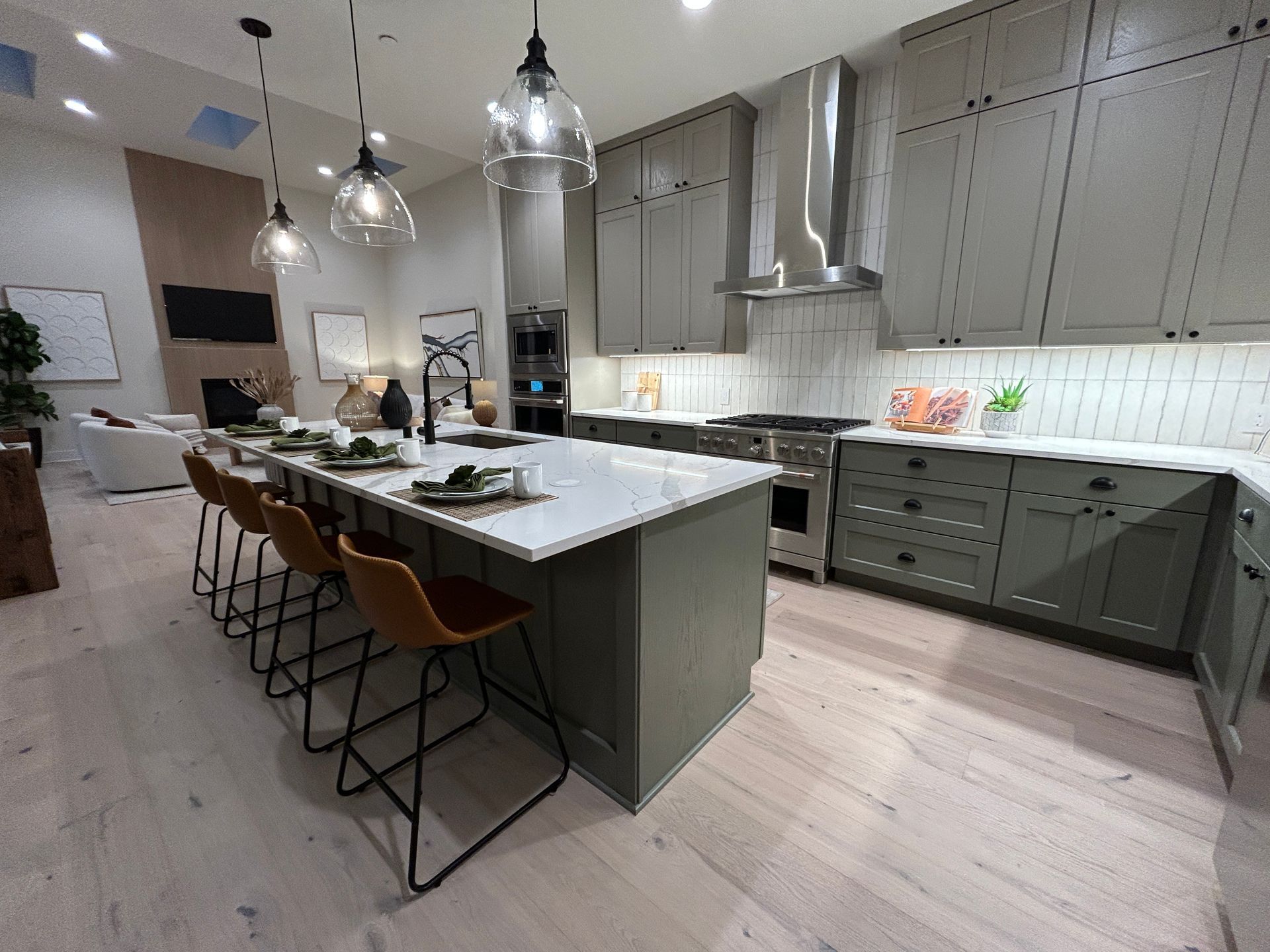 Modern kitchen with gray cabinets, white countertops, and bar seating.