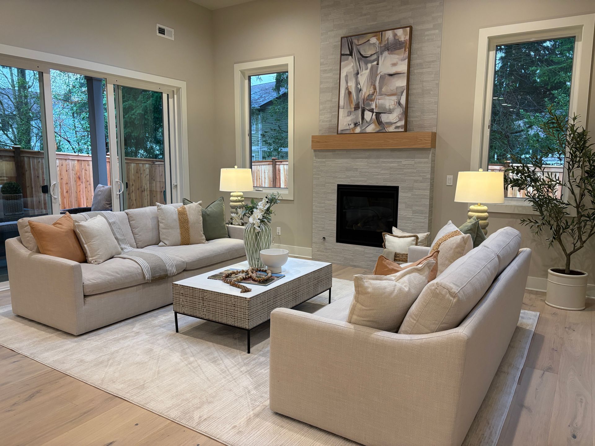 Living room with two cream sofas, fireplace, and light wood floors.