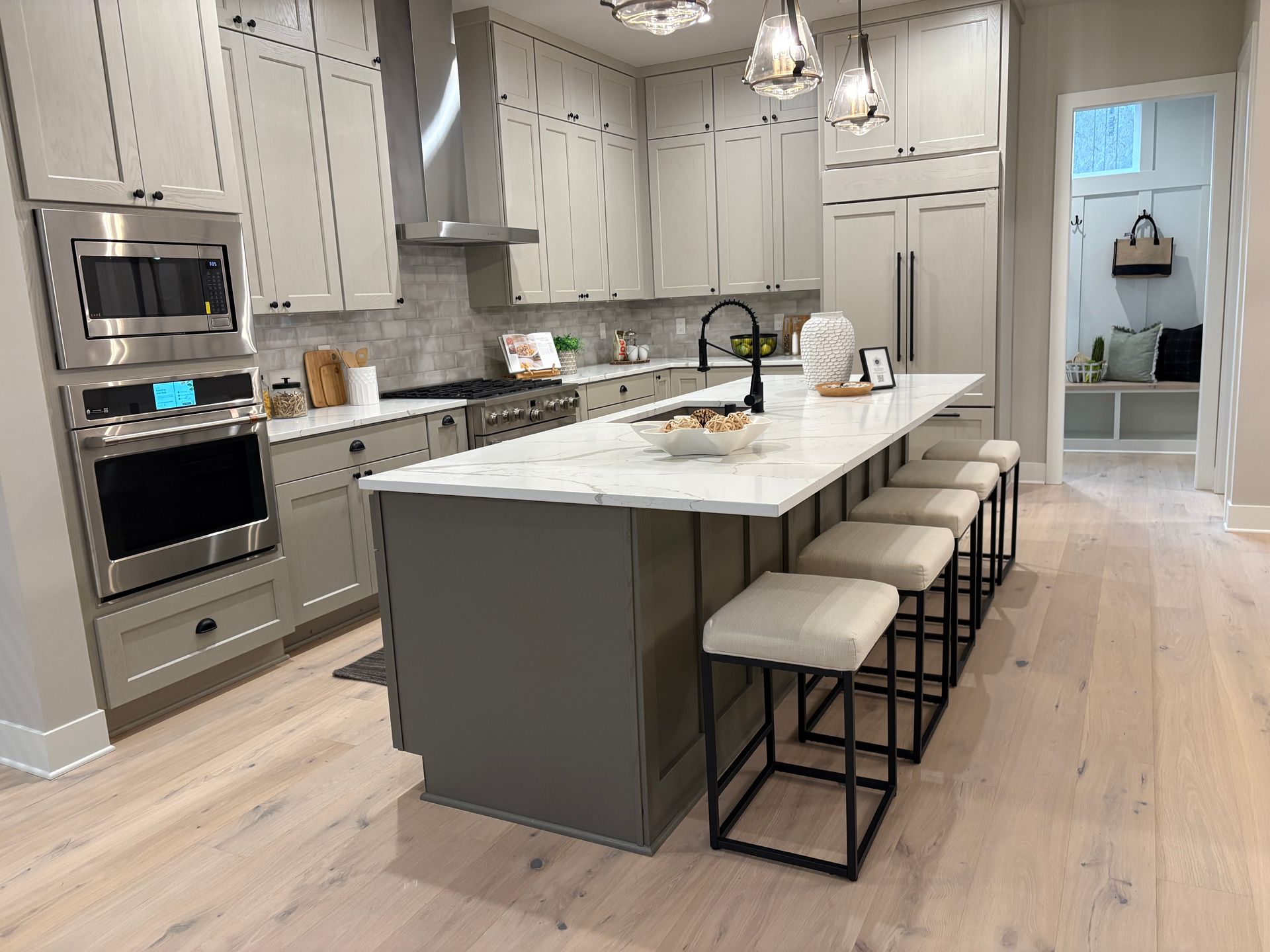 Modern kitchen with gray cabinets, island with stools, and stainless steel appliances.