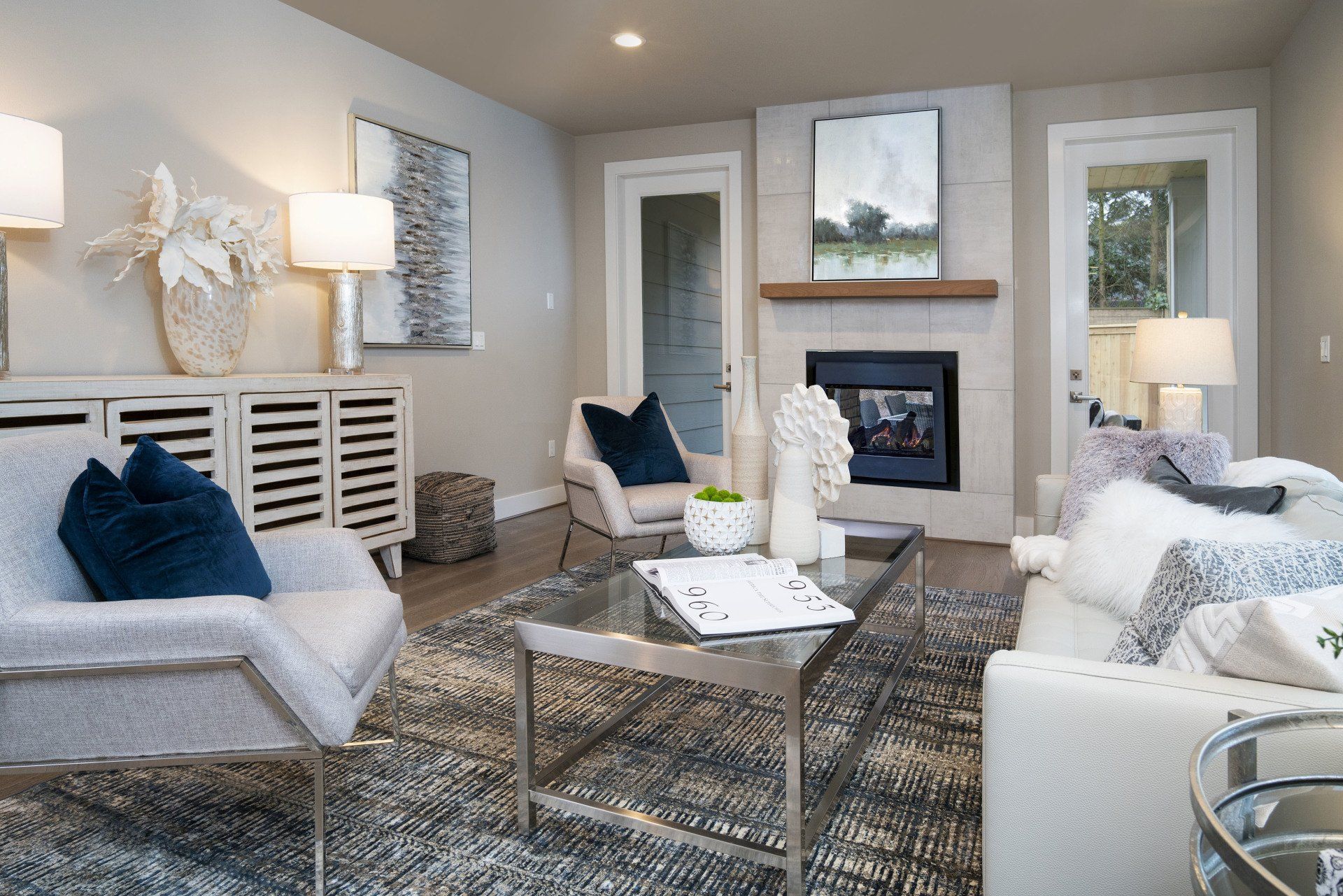 Living room with fireplace, white furniture, gray rug, and modern decor.