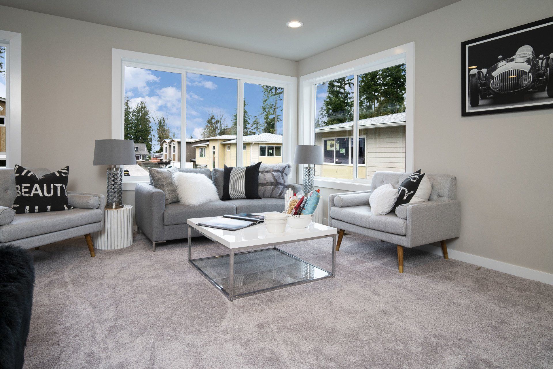 Living room with gray sofa, armchairs, windows, and decor.