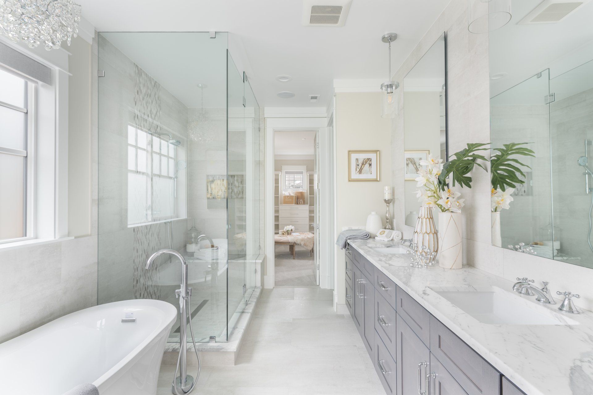 Elegant, bright bathroom with a bathtub, glass shower, double vanity, and long mirror. Neutral color palette.
