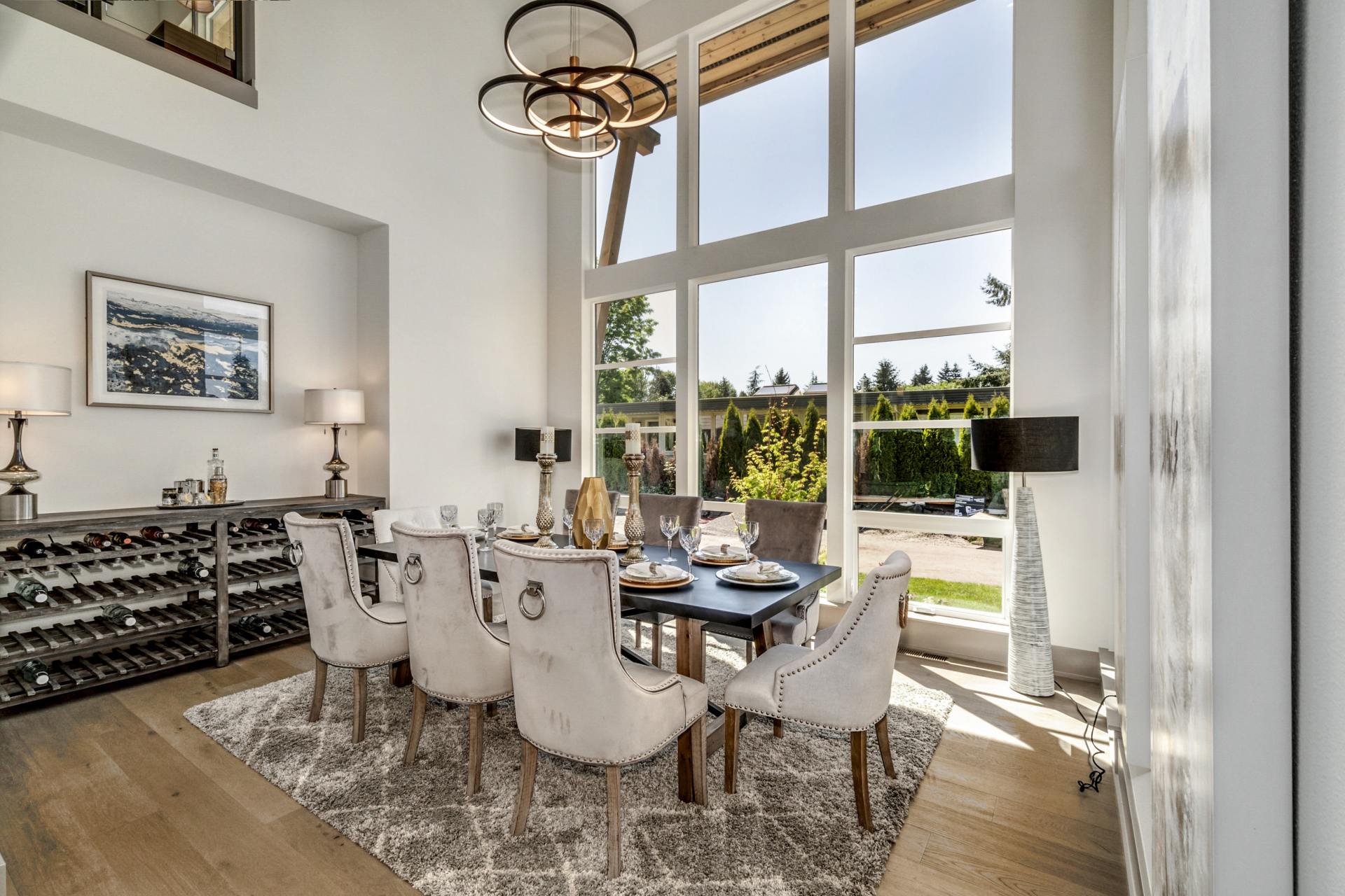 Dining room with a table set for a meal, large windows, and a wine rack.