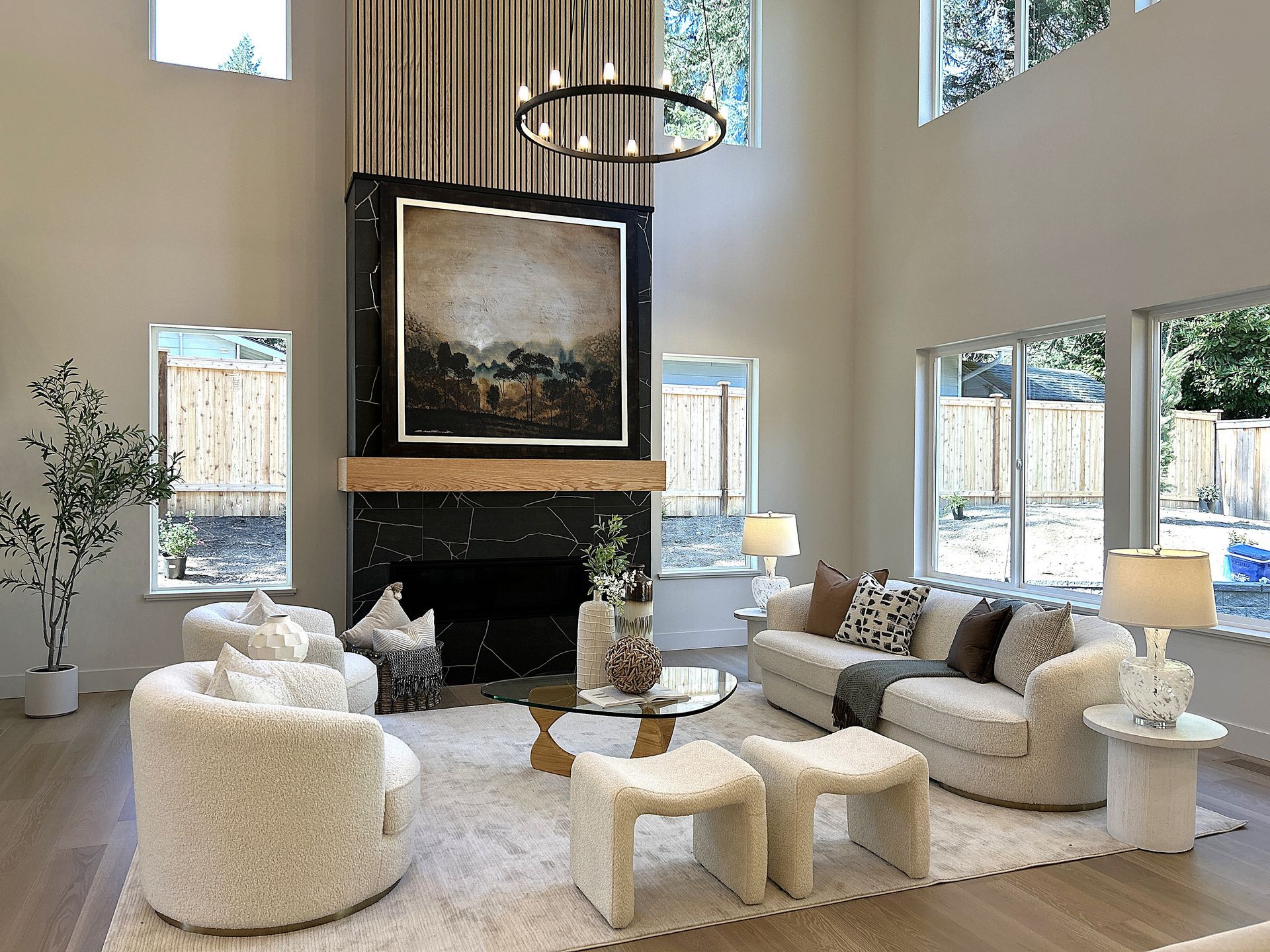 Bright modern living room with fireplace, large windows, white sofas, and round chairs