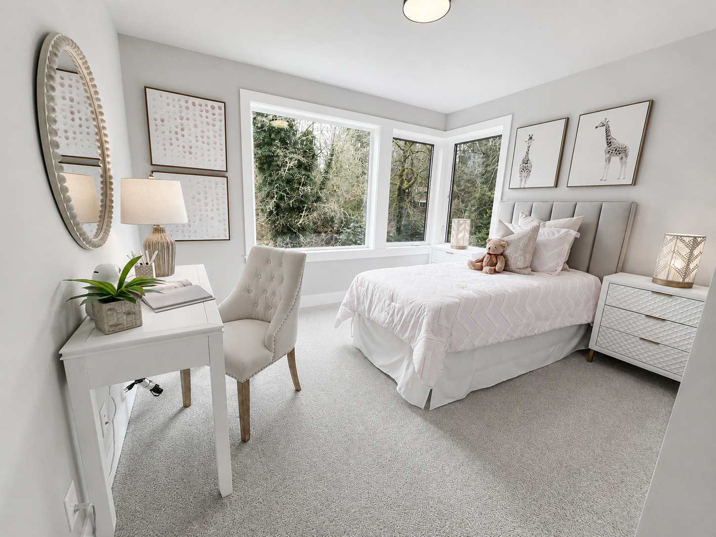 Bright bedroom with white furniture, bed, desk, and large windows overlooking trees