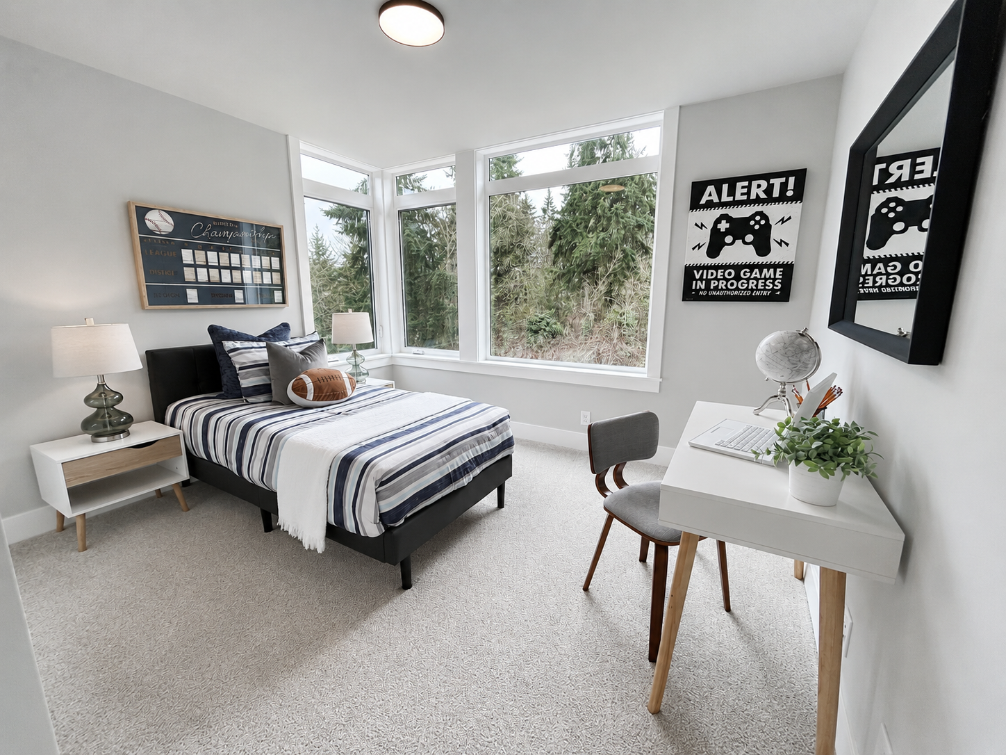 Bright bedroom with a bed by bay windows, white desk chair, and black-and-white wall art.