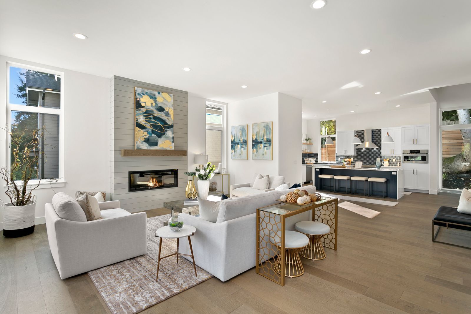 Open-concept living room and kitchen with white furniture, a fireplace, and hardwood floors.