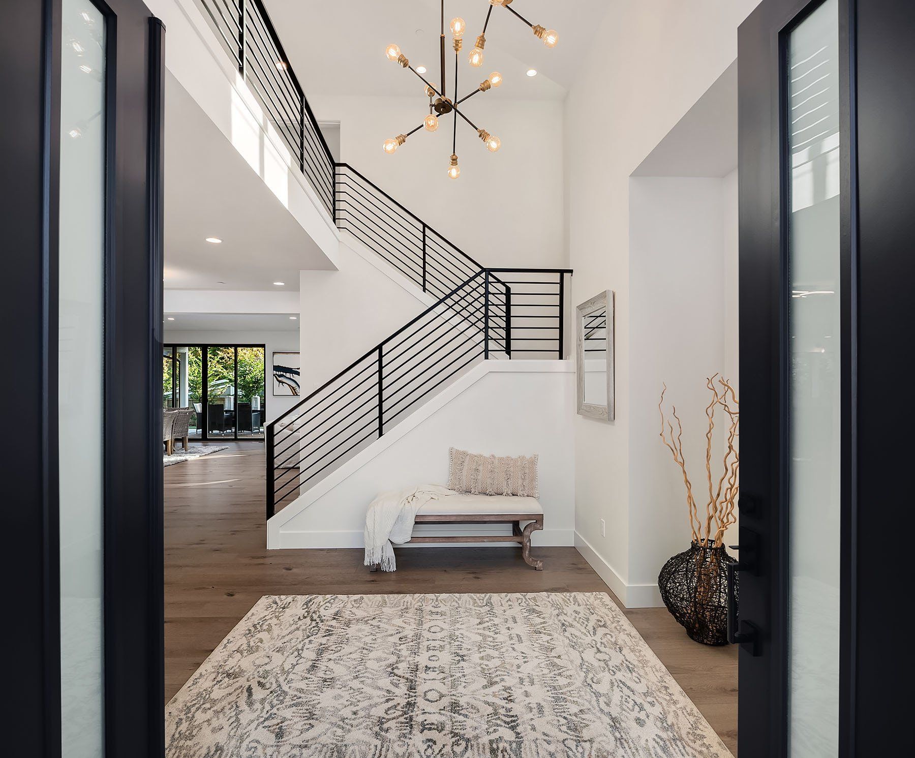 Open entry with a modern staircase, rug, bench, and decorative elements.
