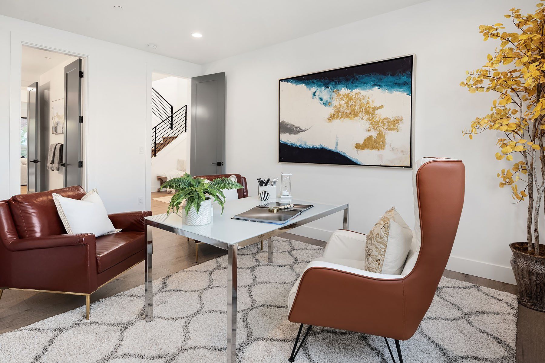 Home office with a leather armchair, desk, art, and rug.