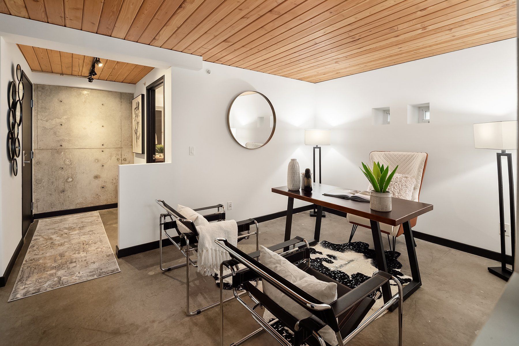 Modern office with wooden ceiling, white walls, two black chairs, desk, and rug.