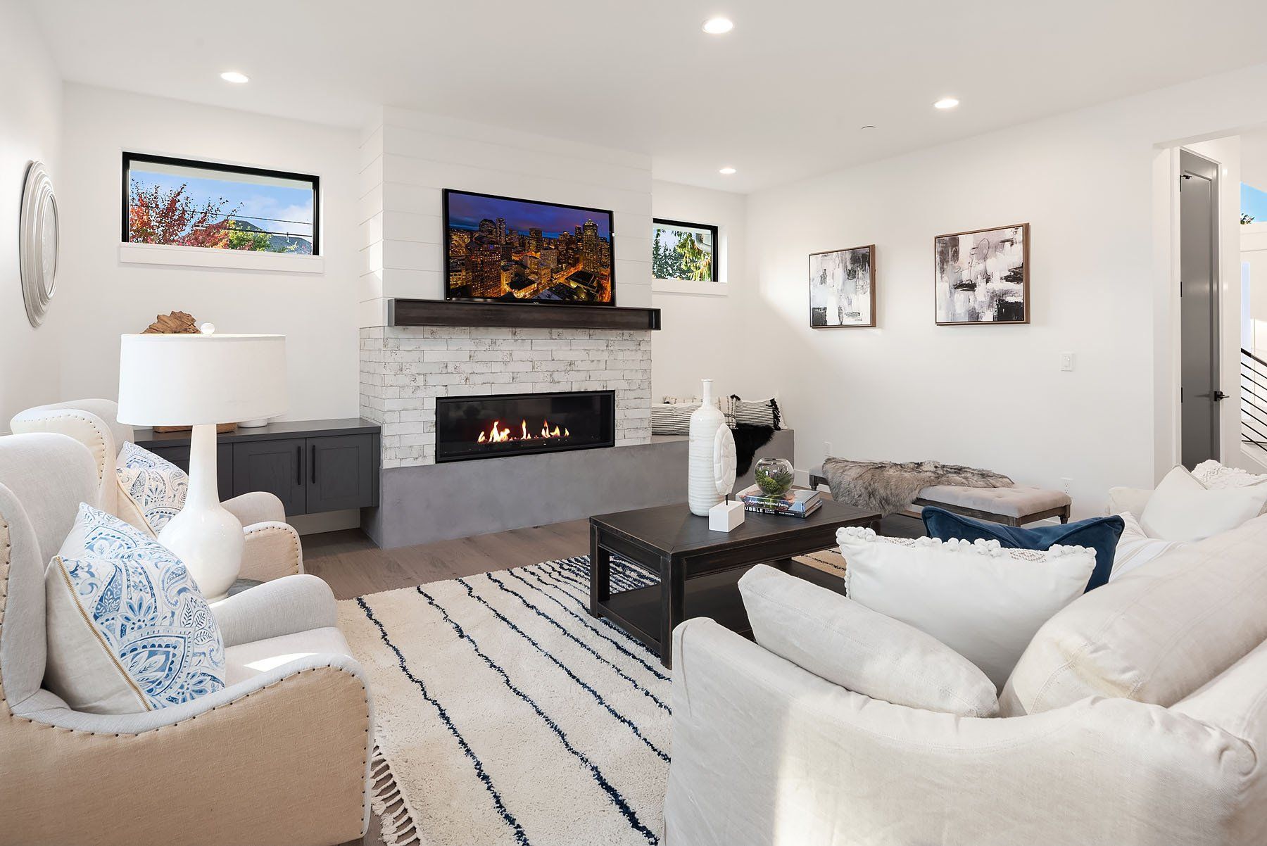 Bright living room with fireplace, white furniture, and various artwork.