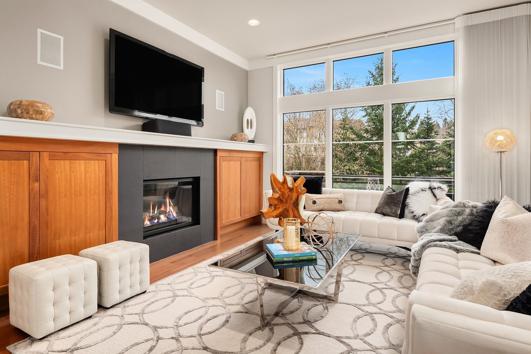 Living room with fireplace, large window, white sofas, and patterned rug.