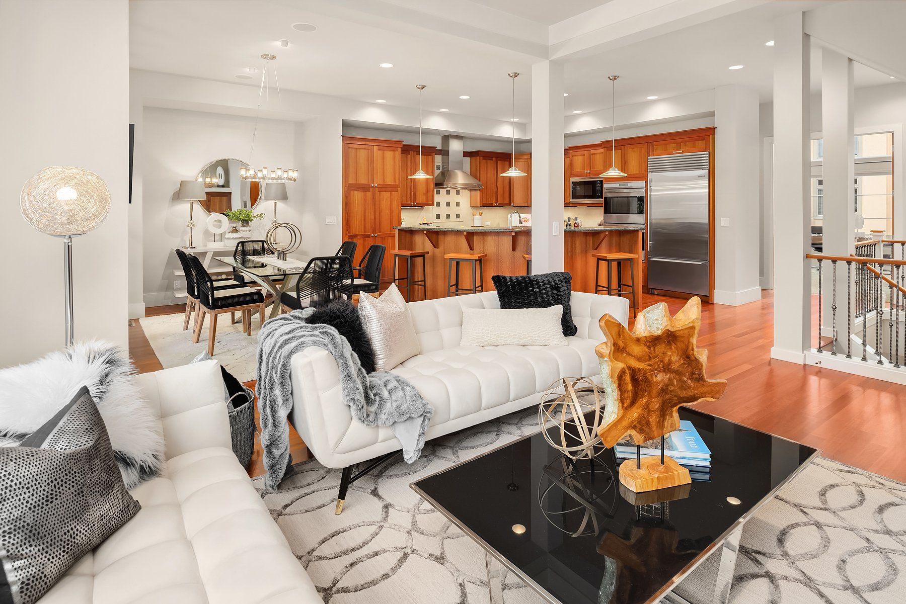 Spacious, modern living space with a white sofa, dark wood floors, and an open kitchen in the background.