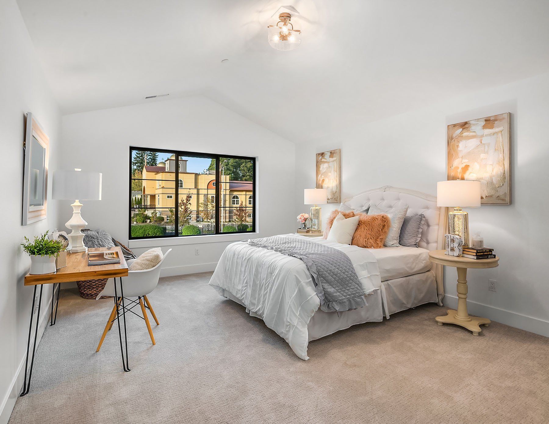 Bright white bedroom with bed, desk, and a window view of other buildings.