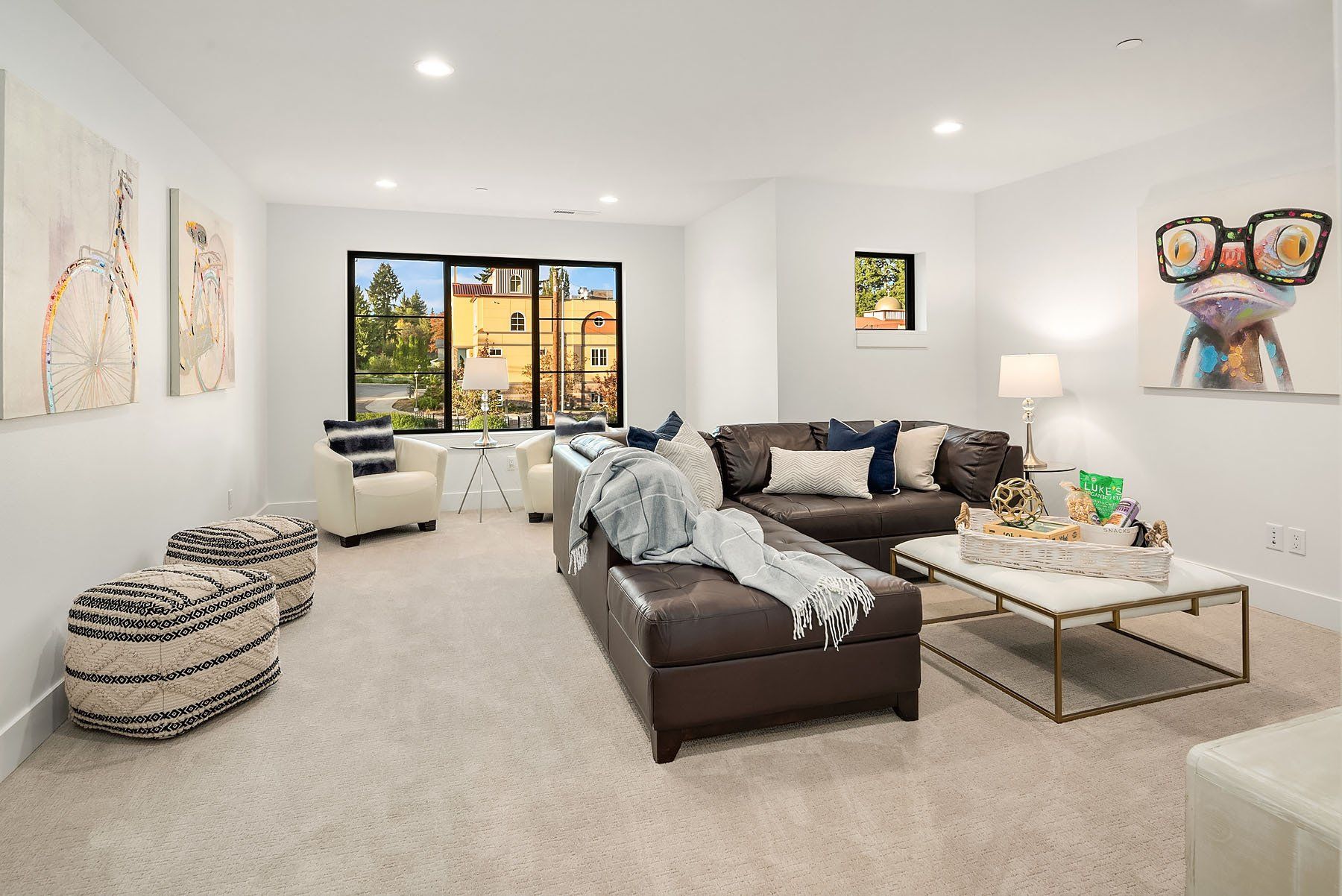 Modern living room with brown sectional, artwork, and a large window.