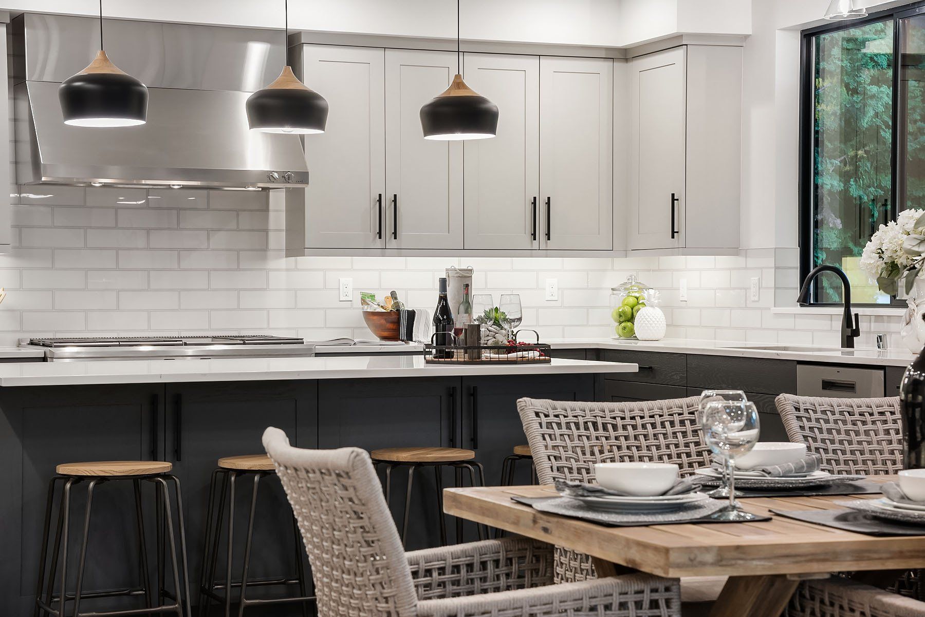 Modern kitchen with island seating, dining table, stainless steel appliances, and white cabinets.