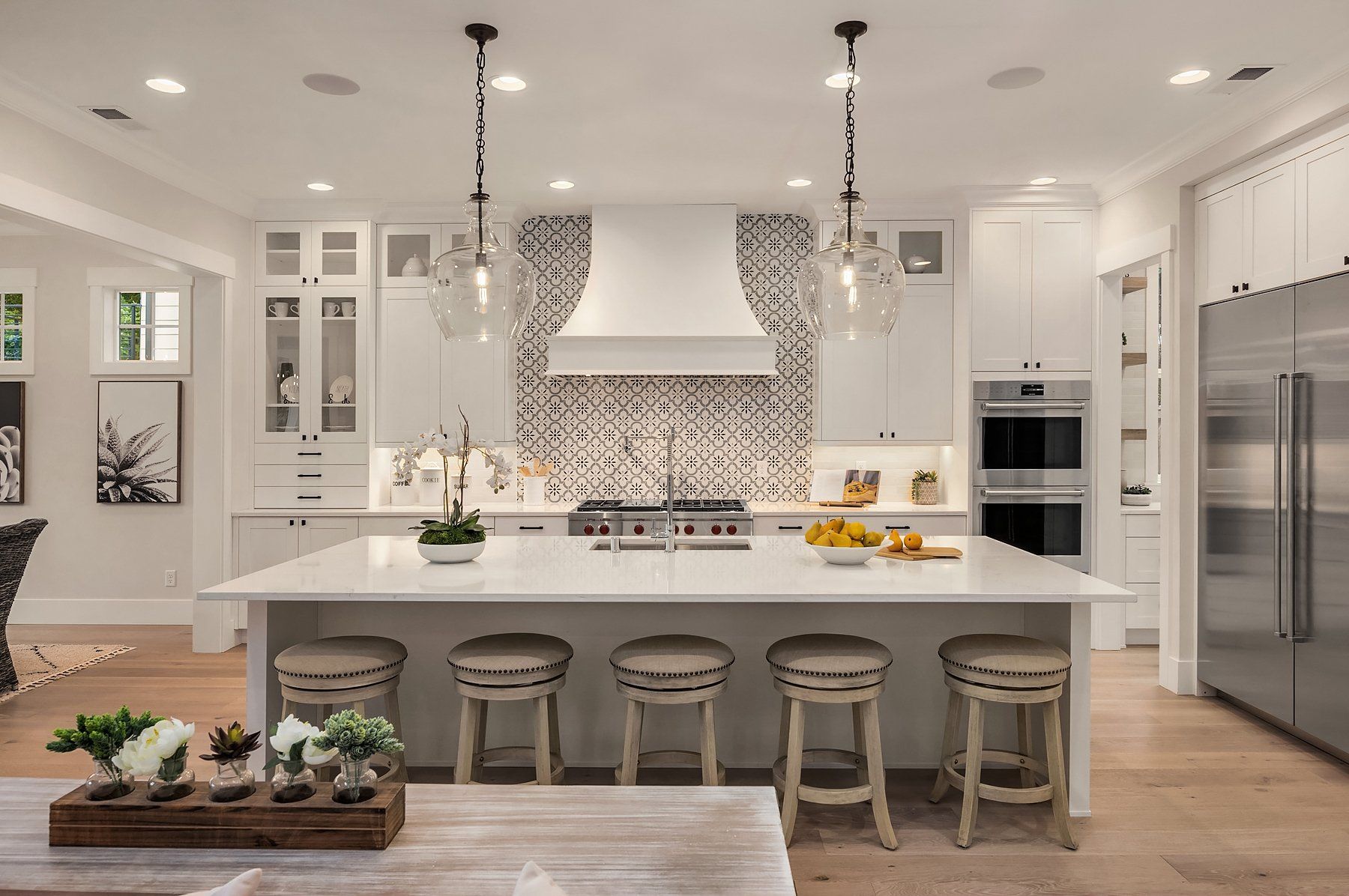 Modern white kitchen with island, pendant lights, and patterned backsplash.